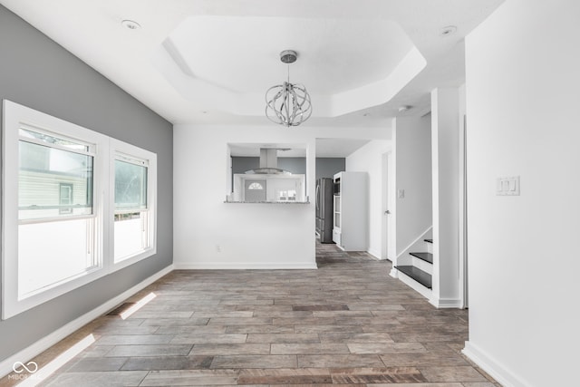 interior space featuring a notable chandelier, hardwood / wood-style floors, and a tray ceiling