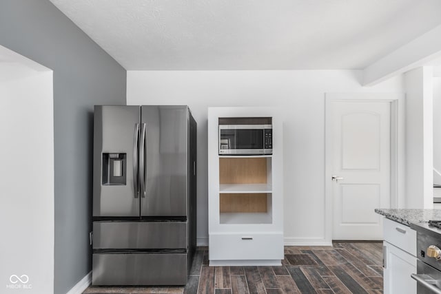 kitchen featuring stainless steel appliances, white cabinets, light stone countertops, dark hardwood / wood-style floors, and a textured ceiling