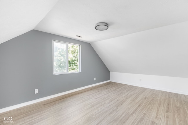 additional living space with vaulted ceiling and light wood-type flooring