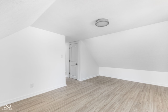 bonus room with light wood-type flooring and vaulted ceiling