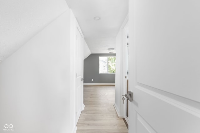 hallway with light hardwood / wood-style flooring and vaulted ceiling