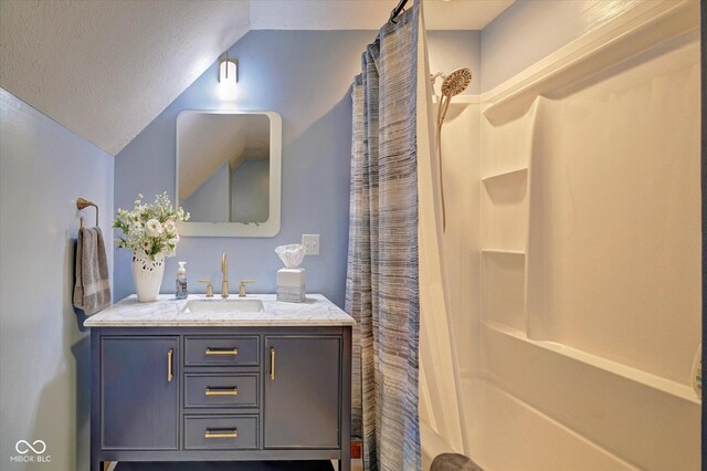 bathroom featuring a textured ceiling, vanity, lofted ceiling, and walk in shower