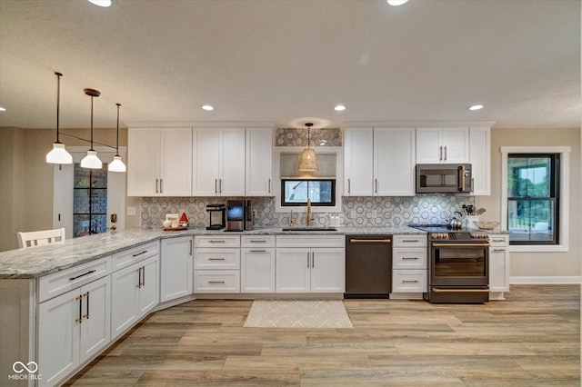 kitchen featuring pendant lighting, kitchen peninsula, sink, appliances with stainless steel finishes, and white cabinetry