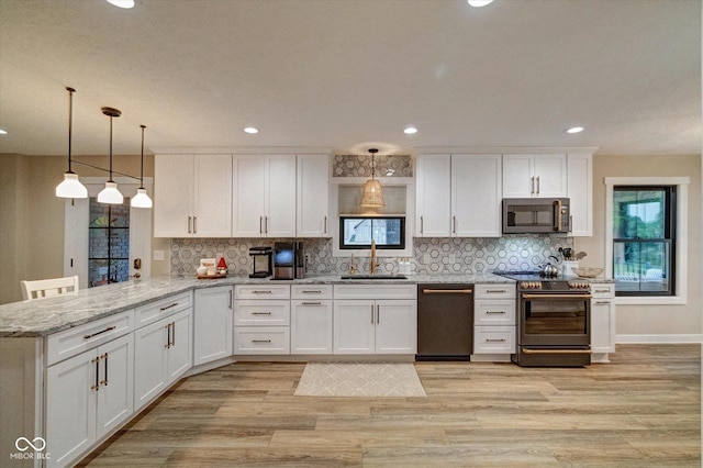 kitchen with sink, white cabinetry, stainless steel appliances, decorative light fixtures, and kitchen peninsula