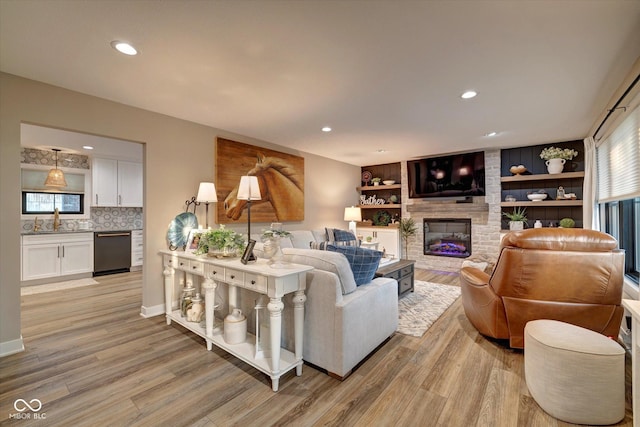 living room with sink, light wood-type flooring, a wealth of natural light, and a fireplace