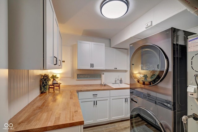 washroom featuring cabinets, light hardwood / wood-style floors, stacked washer and clothes dryer, and sink