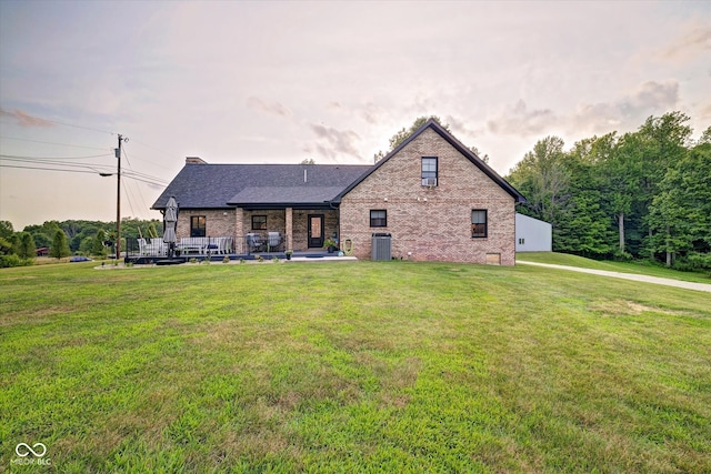 back of house featuring a lawn and central air condition unit