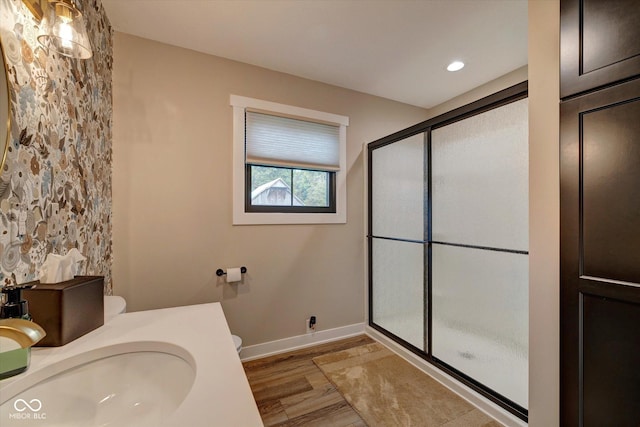 bathroom with hardwood / wood-style floors, a shower with door, sink, and toilet