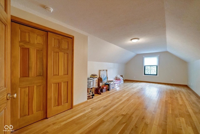 bonus room featuring wood-type flooring, vaulted ceiling, and a textured ceiling