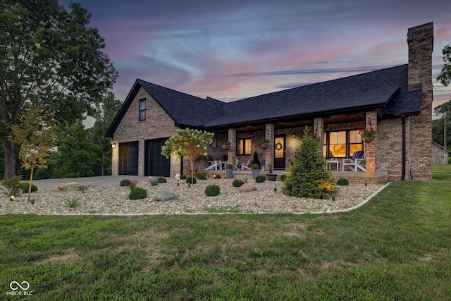 view of front of house featuring a garage, covered porch, and a lawn