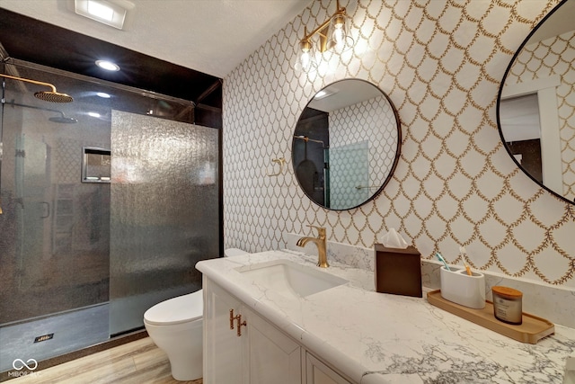 bathroom with vanity, toilet, a tile shower, and wood-type flooring