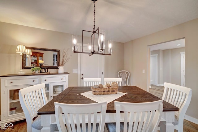 dining space with hardwood / wood-style flooring and a notable chandelier