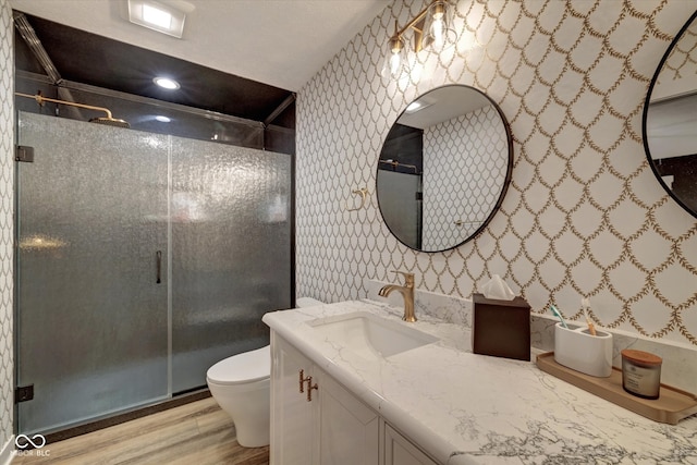 bathroom with hardwood / wood-style floors, vanity, a shower with shower door, and toilet