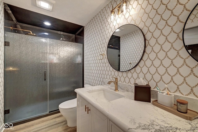 bathroom featuring vanity, toilet, an enclosed shower, and hardwood / wood-style floors