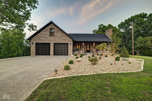 view of front of house featuring a garage, covered porch, and a front lawn