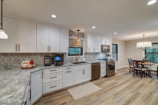 kitchen with decorative light fixtures, white cabinetry, sink, and appliances with stainless steel finishes