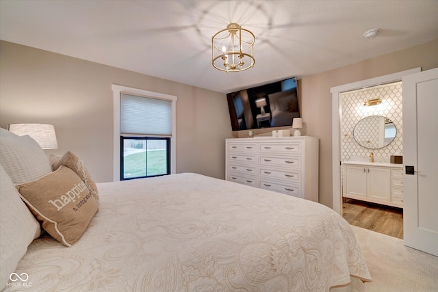 bedroom featuring a chandelier, connected bathroom, and light hardwood / wood-style floors