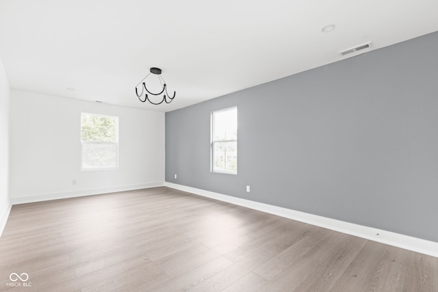 spare room featuring light hardwood / wood-style flooring and a chandelier