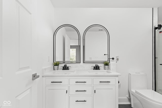 bathroom featuring dual vanity and toilet