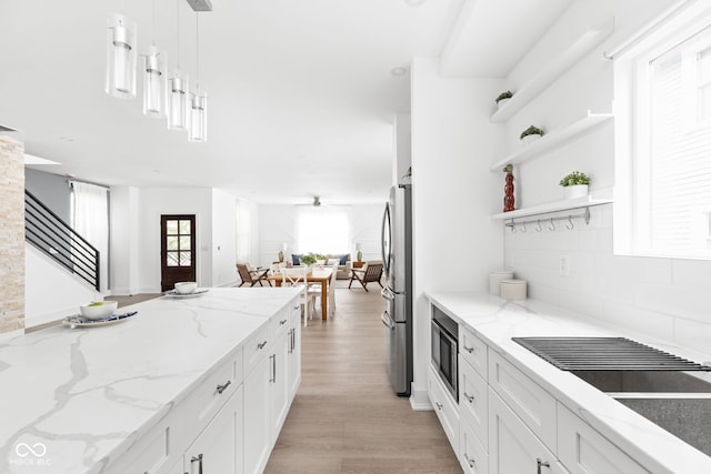 kitchen with light hardwood / wood-style flooring, white cabinetry, appliances with stainless steel finishes, pendant lighting, and light stone countertops