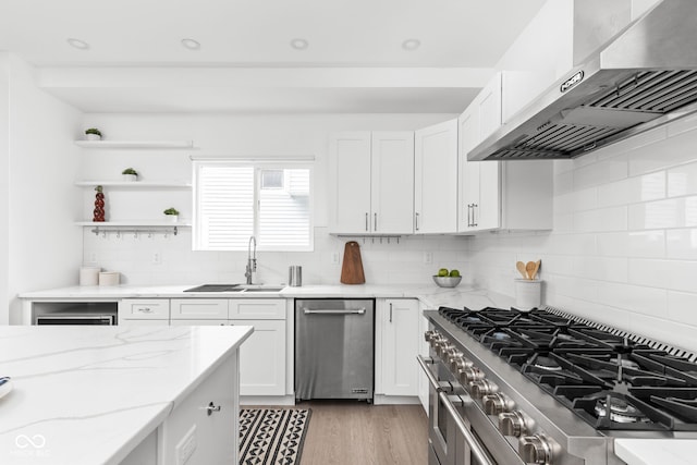 kitchen with decorative backsplash, stainless steel appliances, light hardwood / wood-style flooring, and wall chimney range hood