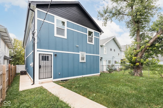 rear view of house featuring central AC unit and a yard