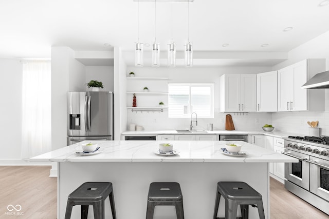 kitchen with light stone countertops, sink, stainless steel appliances, and light hardwood / wood-style floors