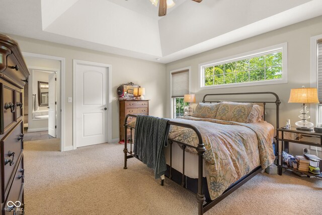 carpeted bedroom featuring ensuite bath, ceiling fan, and a raised ceiling