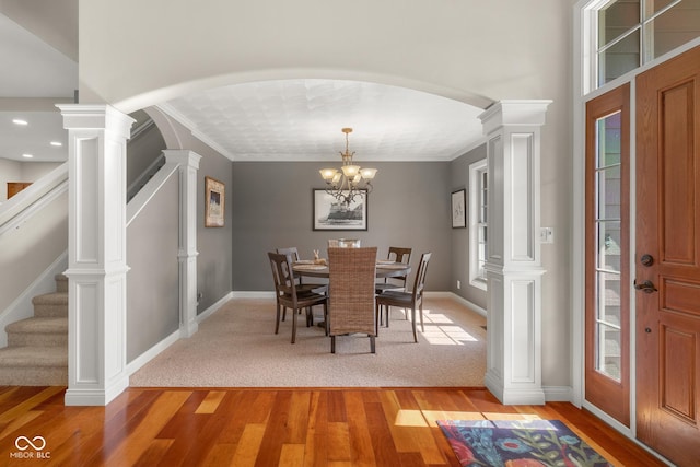 dining room featuring decorative columns, a wealth of natural light, hardwood / wood-style floors, and crown molding