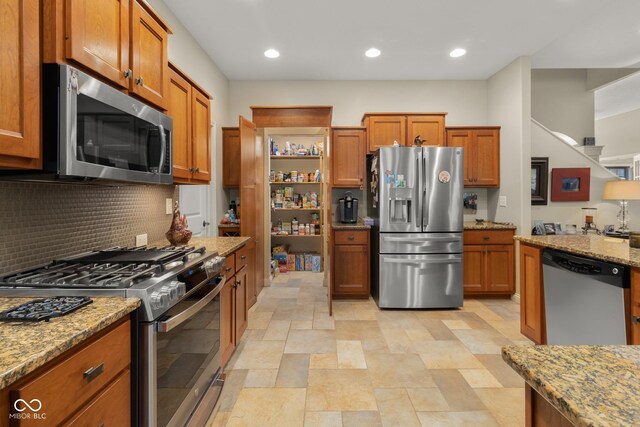 kitchen featuring stainless steel appliances, light stone counters, and tasteful backsplash