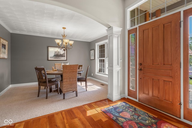 foyer featuring decorative columns, a notable chandelier, crown molding, and light hardwood / wood-style floors