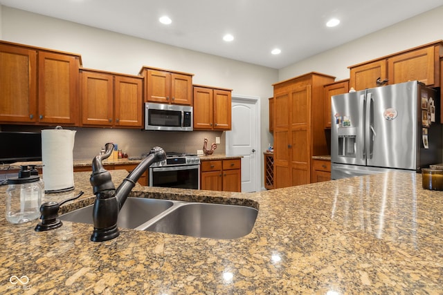 kitchen featuring decorative backsplash, sink, stone countertops, and stainless steel appliances