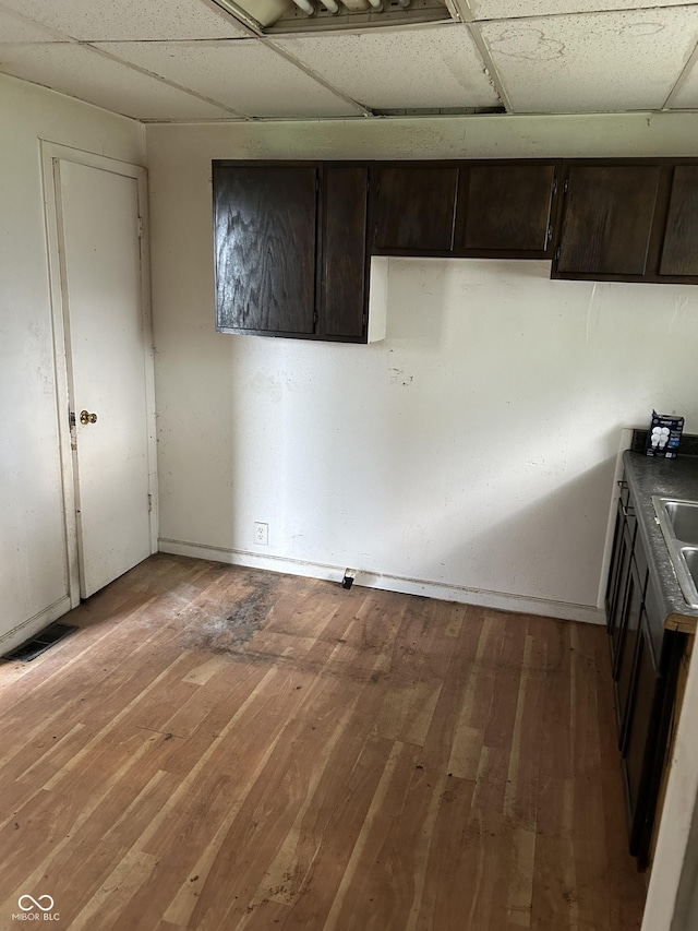 kitchen with hardwood / wood-style floors, dark brown cabinets, and a drop ceiling