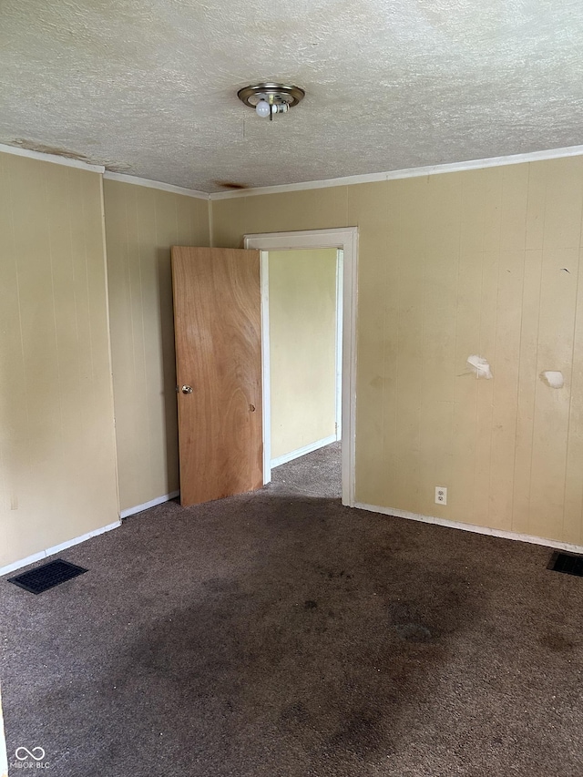 unfurnished room with ornamental molding, a textured ceiling, and dark colored carpet