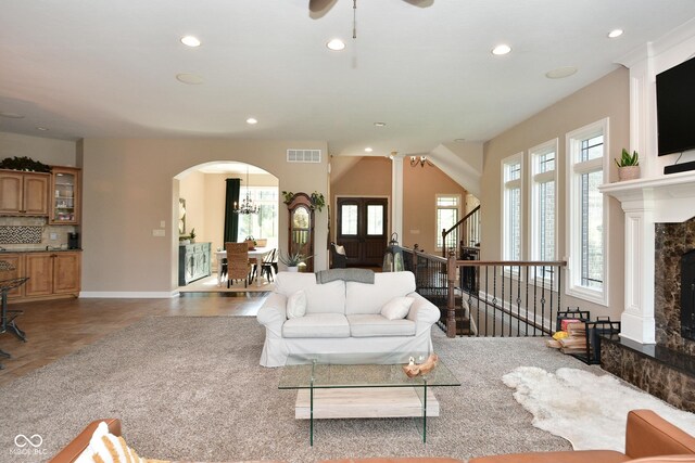 living room with a fireplace, tile patterned flooring, and ceiling fan with notable chandelier