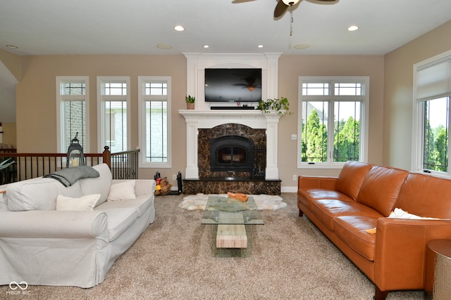 living room with light colored carpet, a high end fireplace, a wealth of natural light, and ceiling fan