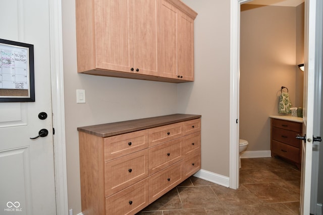 interior space featuring tile patterned flooring, baseboards, and toilet