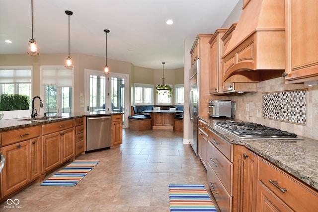 kitchen featuring decorative light fixtures, stainless steel appliances, sink, dark stone countertops, and light tile patterned floors