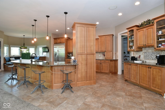 kitchen with hanging light fixtures, stainless steel fridge with ice dispenser, a large island, a breakfast bar, and light tile patterned floors