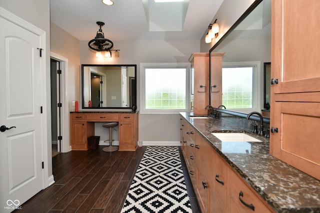 bathroom featuring wood finish floors, a healthy amount of sunlight, vanity, and baseboards