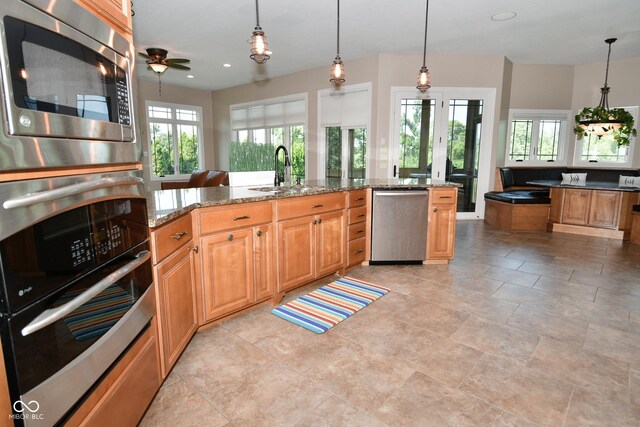 kitchen with light tile patterned flooring, a wealth of natural light, appliances with stainless steel finishes, and sink