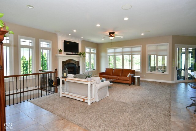 living room featuring plenty of natural light, a premium fireplace, ceiling fan, and light tile patterned floors