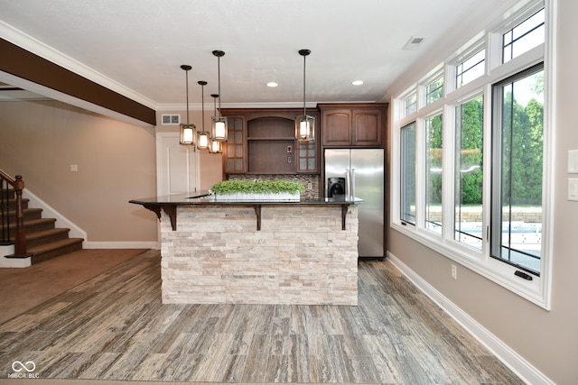 kitchen featuring stainless steel fridge, a wealth of natural light, a kitchen bar, and hardwood / wood-style flooring