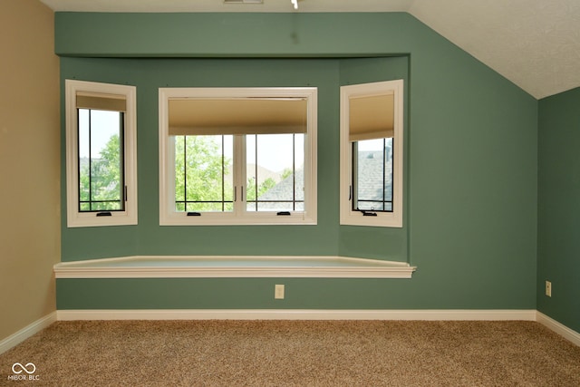 carpeted spare room featuring vaulted ceiling