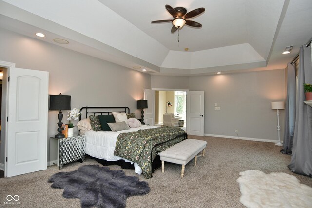 carpeted bedroom with ceiling fan and a raised ceiling