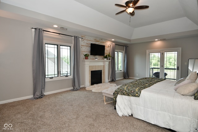 bedroom featuring carpet flooring, access to exterior, ceiling fan, a tray ceiling, and a fireplace