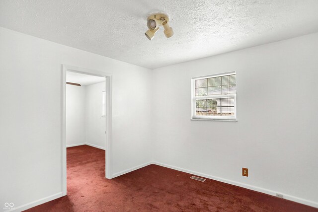 carpeted empty room featuring a textured ceiling