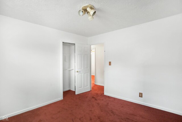 unfurnished bedroom with a closet, a textured ceiling, and dark carpet