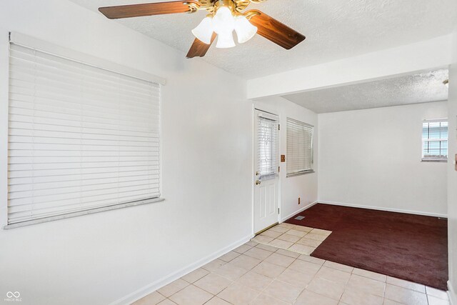 spare room with a textured ceiling, light colored carpet, and ceiling fan