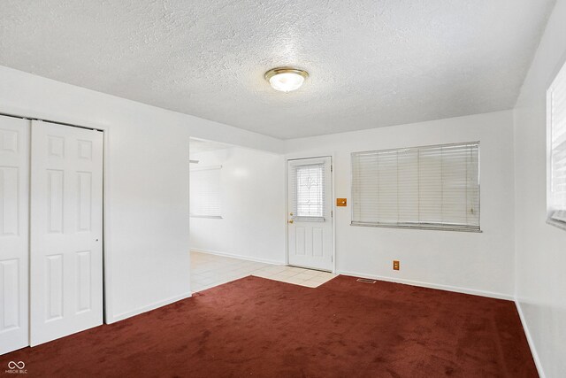 unfurnished bedroom with light carpet, a closet, and a textured ceiling